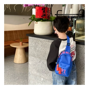 Rückansicht eines Kindes mit königsblauer Nylon-Brusttasche mit rosa ASH-Schriftzug