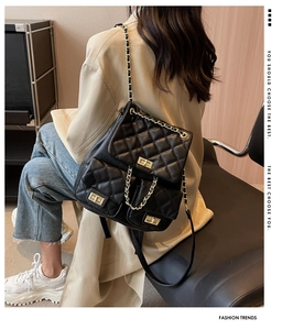 Detail of black quilted faux leather backpack with gold twist locks and chain straps