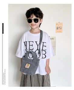 Close-up of gray corduroy kids handbag with cute bear patch worn by young model