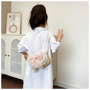 Detail van strooien kindertas met roze organza strik, kant en parelhangers