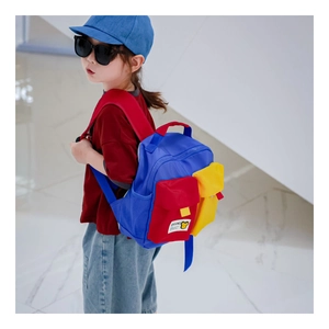 Kid wearing blue, red, and yellow contrast canvas backpack in a modern setting