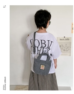 Detailed view of gray corduroy kids crossbody bag with cute bear patch worn by child