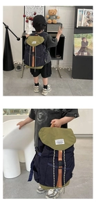 Détail d'un sac à dos enfant bicolore avec panneaux bleu marine, vert et sangles latérales