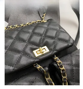 Detail of black caviar leather quilting and gold chain strap on a mini backpack