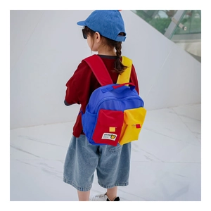 Detail view of colorful contrast children canvas backpack worn by a boy in a modern setting