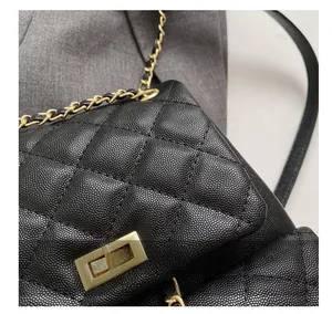 Detail of black caviar leather with diamond quilting and gold rotating metal lock