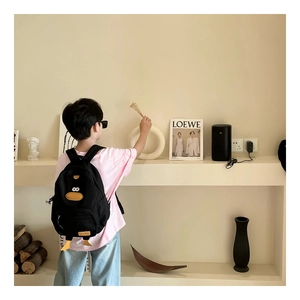 Detailed side view of a black canvas child backpack with a cute 3D cartoon duck design