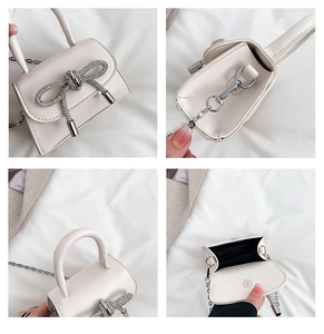 Detail showing white mini handbag with rhinestone bow, chain strap and magnetic closure