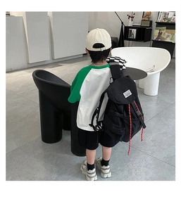 Vue arrière du sac à dos enfant en toile noire avec rabat à boucle et cordon de serrage rouge
