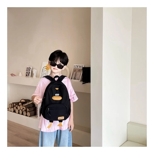 Detail of cute black cartoon duck backpack with 3D beak and orange feet on a young boy