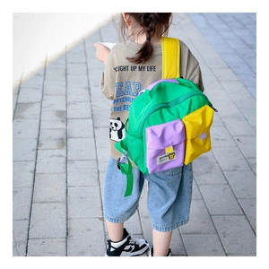 Detail of color-block kids canvas backpack showing multiple pockets and bear patch design