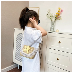 Detail van een kind met strooien crossbodytas met kant en een zeester-symbool