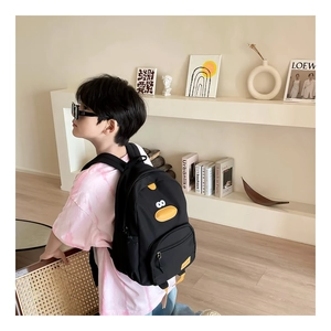 Detail of child's black canvas backpack featuring a cute yellow duck cartoon and straps