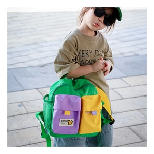 Detail shot of multi-pocket contrast color kids backpack worn by a model in outdoor setting