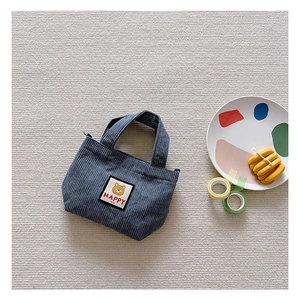 Detail of greyish-blue corduroy kids bag featuring a cute bear patch and HAPPY embroidery