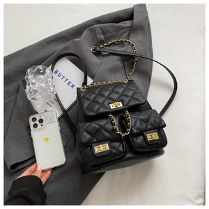 Detail of black quilted leather backpack featuring gold twist locks and chain straps