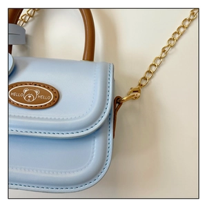 Close-up of light blue mini bag featuring brown teddy bear patch and golden chain strap
