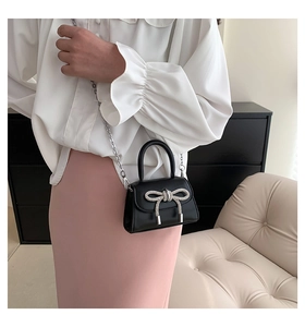Mini black leather crossbody bag featuring a silver rhinestone bow and chain strap