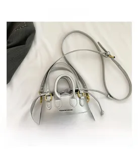 Close-up of silver mini handbag featuring a grey drawstring inner pouch and long strap