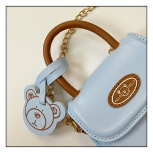 Detail of light blue mini bear bag with gold chain strap and textured leather finish