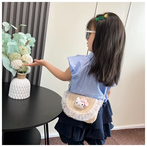 Detail van kinderstro-tas met witte kanten rand en schattige pluche kattenpop