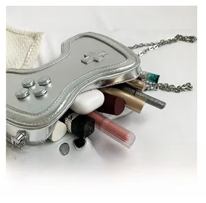 Silberne Handtasche im Game-Controller-Design zeigt den Innenraum für Zubehör