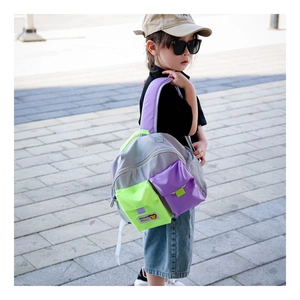 Detail of color-block kids backpack with grey body and neon green pockets on child model