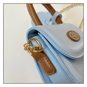 Detail of light blue mini handbag featuring brown handle and gold metal chain links