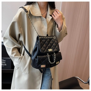 Detail of black quilted backpack with gold chain straps and classic rhombic pattern
