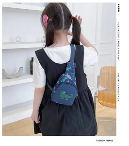 Vue arrière d'un enfant portant un sac de poitrine dinosaure bleu avec broderie
