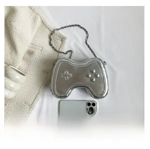 Nahaufnahme der silbernen Mini-Tasche in Gamecontroller-Form mit Metallkette auf Tuch
