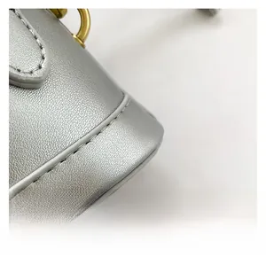 Macro view of textured silver leather handbag with gold metal ring and neat stitching