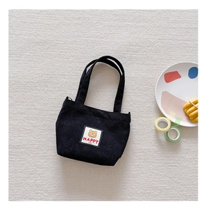 Detail of black corduroy mini handbag with cute cartoon bear patch and happy text