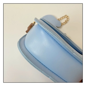 Detail of light blue mini bag featuring smooth faux leather texture and gold chain strap
