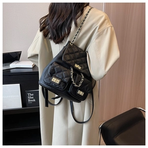 Detail of black quilted backpack with gold twist locks and leather chain straps