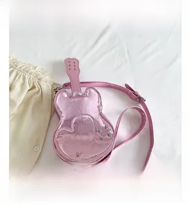 Detail of guitar shaped crossbody bag in bright pink patent leather with heart stitching
