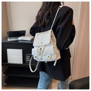 Close-up of white quilted backpack with gold rotary locks and chain straps on model