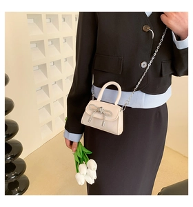 Close-up of cream PU leather mini bag featuring a rhinestone bow and silver chain strap