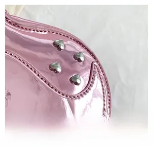 Close-up of metallic pink patent leather bag with silver heart-shaped rivets and stitching