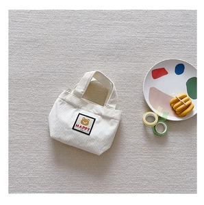 Close-up of white corduroy mini handbag featuring a cute cartoon bear and HAPPY text label