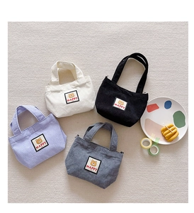 Detail view of colorful corduroy mini handbags featuring cute bear patches and top handles