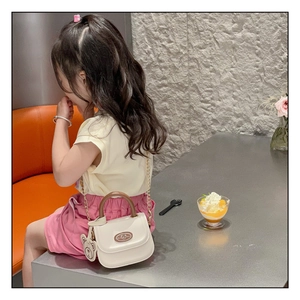 Girl wearing white PU leather mini bag with wooden handle, bear charm, and gold chain