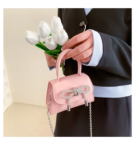 Detailed close-up of pink mini PU handbag featuring a sparkling silver rhinestone bow decoration