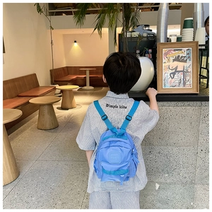 Vue arrière d'un enfant portant un mini sac à dos bleu clair léger dans un café