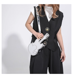 Silver guitar shaped crossbody bag with mirror finish and wide strap on model