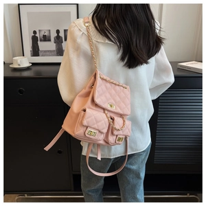 Pink quilted backpack with golden twist lock and chain straps worn by a female model