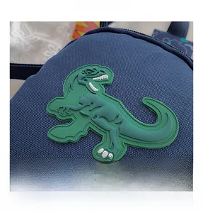 Gros plan sur la texture du tissu bleu et le patch dinosaure 3D vert du sac enfant