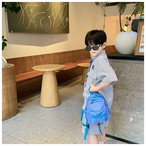 Détail du sac à dos enfant bleu imperméable avec poche zippée porté par un mannequin