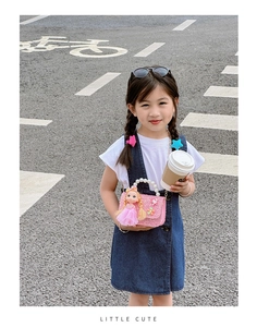 Close-up of pink glitter kids bag with doll decor, pearl handle and chain strap