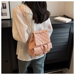 Close-up of pink quilted mini backpack featuring gold chain straps and metal twist locks